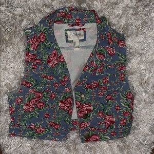 A blue jeans vest with green and red flowers.